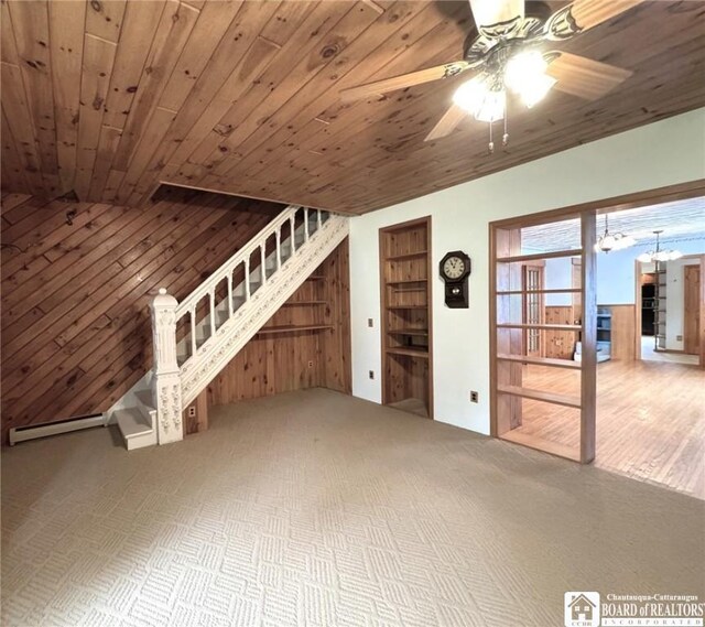 unfurnished living room with wood ceiling, ceiling fan with notable chandelier, and wood walls