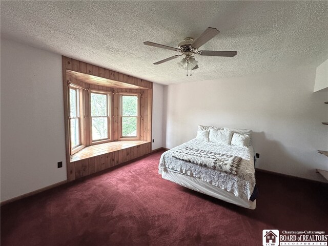 carpeted bedroom featuring ceiling fan, a textured ceiling, and wood walls