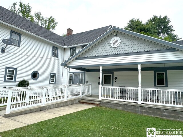 rear view of property with a lawn and a porch