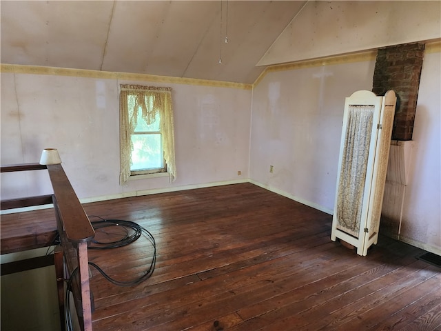 spare room featuring dark wood-type flooring and lofted ceiling