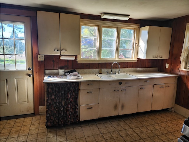 kitchen featuring a wealth of natural light, wooden walls, and sink