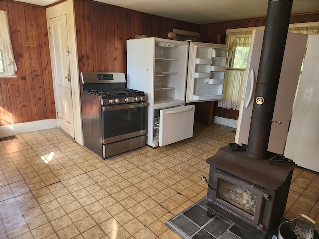 kitchen featuring stainless steel gas stove, a wood stove, and wooden walls