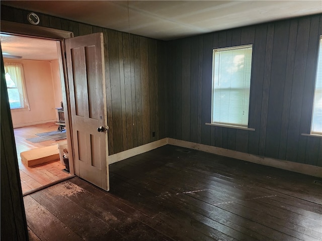 unfurnished room featuring wood walls and dark hardwood / wood-style flooring