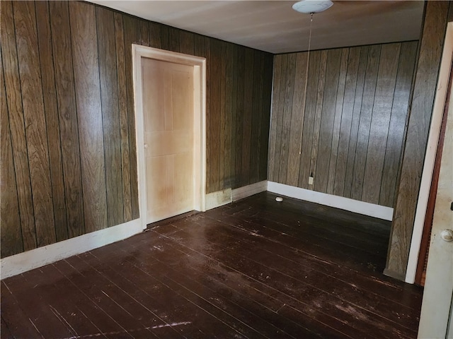 spare room with wood walls and dark hardwood / wood-style floors