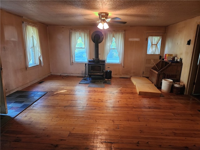 interior space with light hardwood / wood-style floors, a wood stove, and ceiling fan