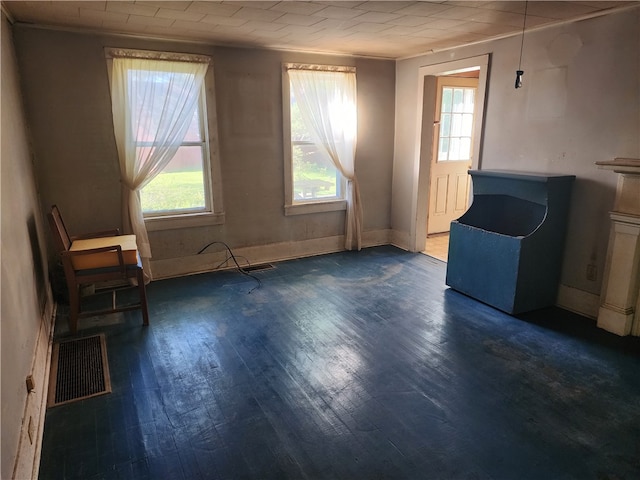 empty room featuring a healthy amount of sunlight, dark hardwood / wood-style floors, and ornamental molding