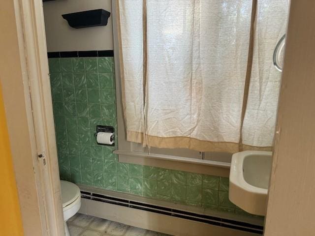 bathroom featuring tile walls, toilet, and baseboard heating