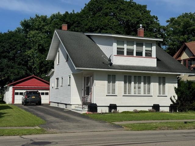 view of front of home with a garage, a front lawn, and an outdoor structure