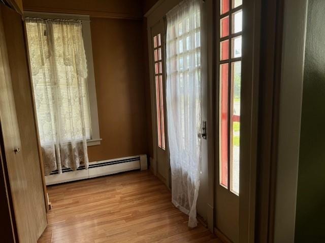 empty room featuring light wood-type flooring and a baseboard heating unit