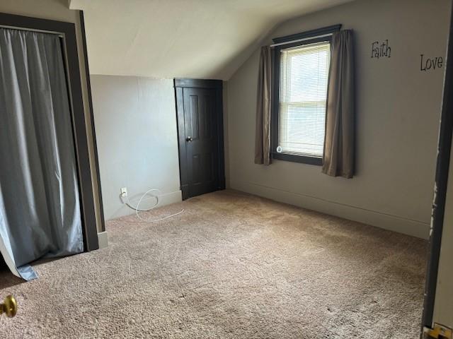 unfurnished bedroom featuring lofted ceiling, a closet, and carpet floors