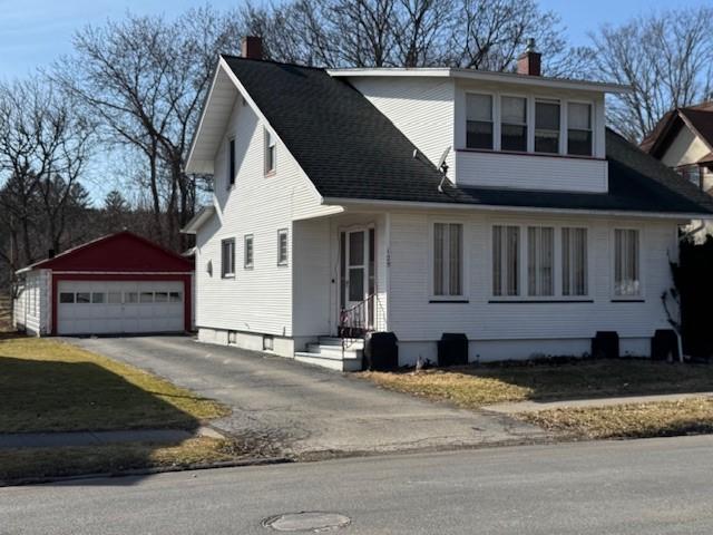 view of front of property featuring entry steps, a chimney, a detached garage, and an outdoor structure