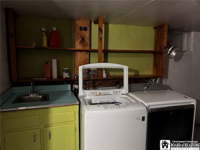 clothes washing area with cabinets, sink, and washer and clothes dryer