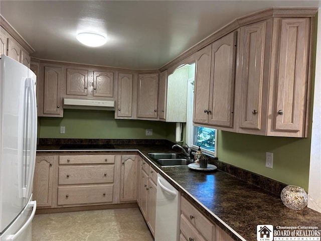 kitchen with white appliances, light brown cabinetry, and sink