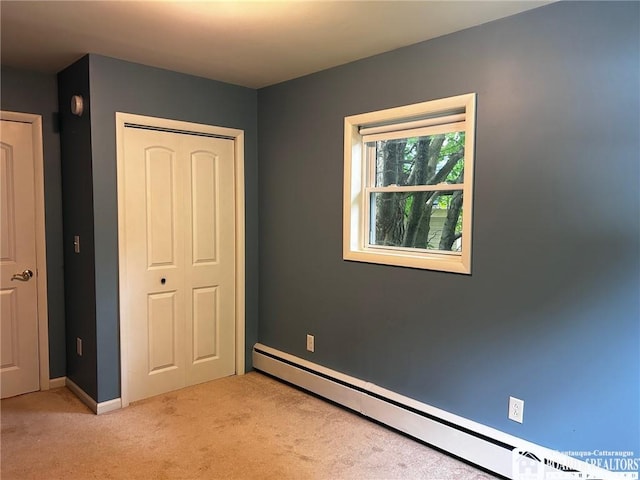 unfurnished bedroom featuring a baseboard heating unit, light colored carpet, and a closet