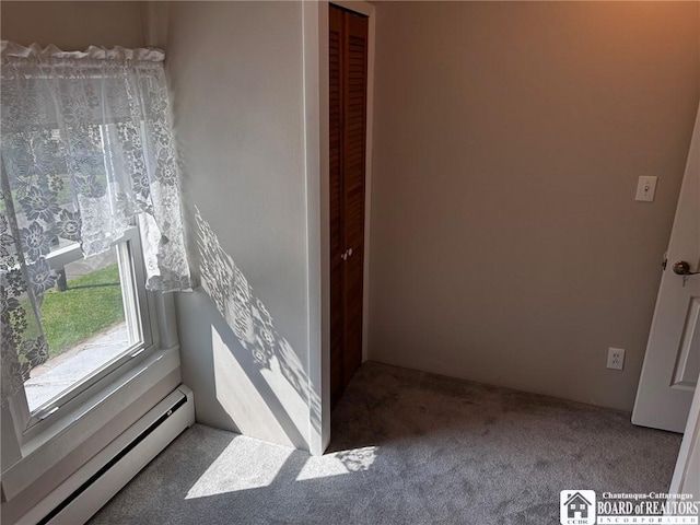 carpeted empty room with a baseboard radiator