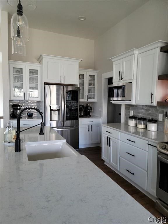 kitchen with appliances with stainless steel finishes, backsplash, white cabinets, and sink