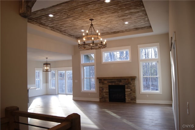 unfurnished living room featuring a fireplace, a notable chandelier, dark hardwood / wood-style floors, a tray ceiling, and wooden ceiling