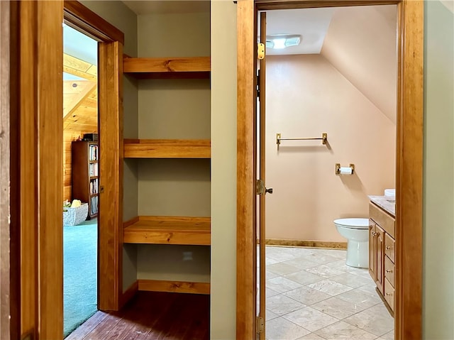 bathroom with vaulted ceiling, vanity, and toilet