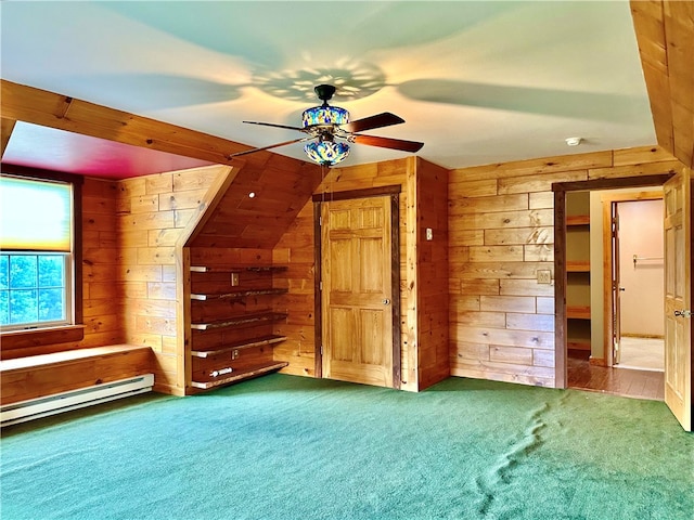 additional living space featuring ceiling fan, baseboard heating, wood walls, and carpet