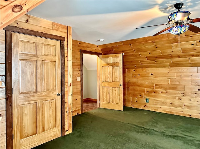 unfurnished bedroom featuring wooden walls, ceiling fan, and dark carpet