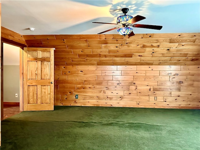 spare room featuring carpet, wooden walls, and ceiling fan