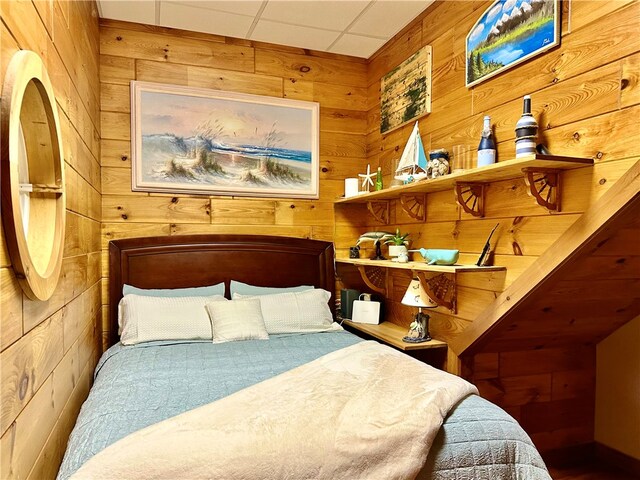 bedroom featuring wooden walls and a paneled ceiling