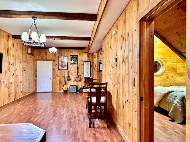 interior space featuring a notable chandelier, wooden walls, beamed ceiling, and hardwood / wood-style flooring