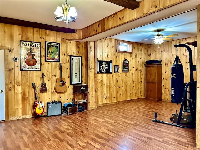 exercise room featuring wood-type flooring, wooden walls, and ceiling fan