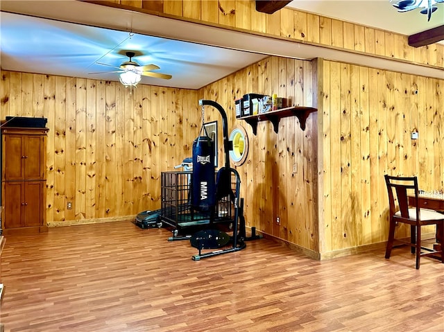 workout room with wooden walls, ceiling fan, and light hardwood / wood-style flooring