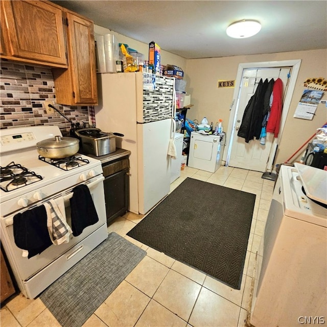 kitchen featuring washer / clothes dryer, light tile patterned floors, backsplash, and white appliances