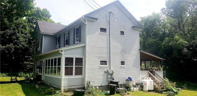 view of side of property featuring a sunroom, central AC unit, and a lawn