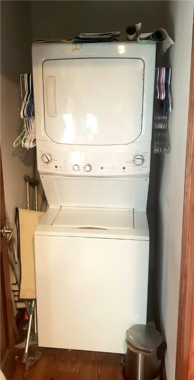 laundry room featuring stacked washer and dryer and dark hardwood / wood-style floors