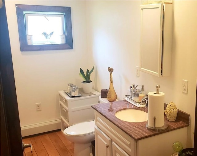 bathroom with hardwood / wood-style flooring, vanity, a baseboard heating unit, and toilet