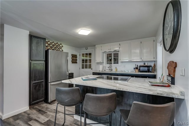 kitchen with white cabinetry, dark hardwood / wood-style floors, black appliances, and kitchen peninsula