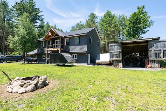 back of house featuring a fire pit and a lawn