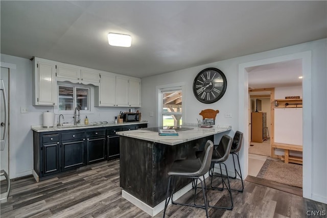 kitchen with white cabinetry, dark hardwood / wood-style floors, kitchen peninsula, and sink