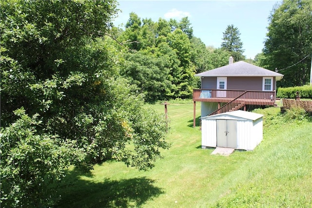 rear view of house with an outbuilding, a storage unit, a lawn, and a wooden deck