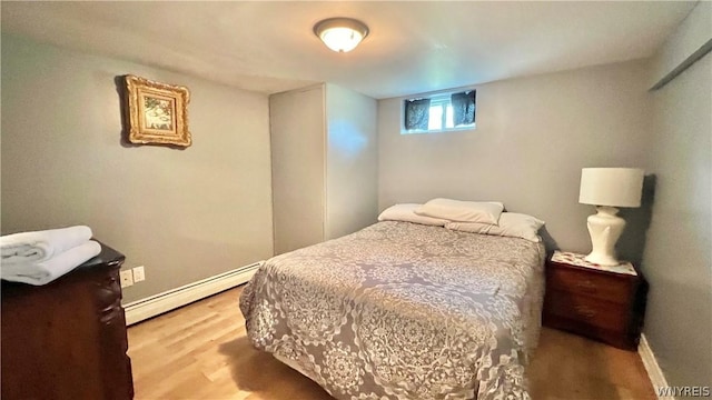 bedroom with light hardwood / wood-style floors and a baseboard heating unit