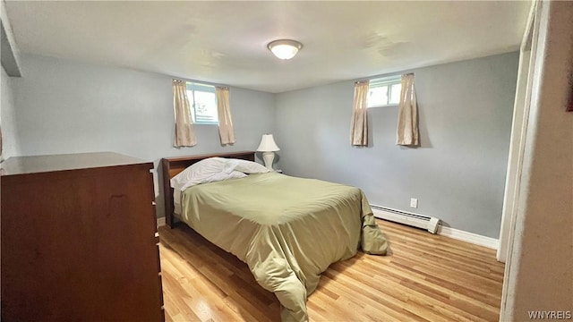 bedroom with multiple windows, a baseboard radiator, and light wood-type flooring