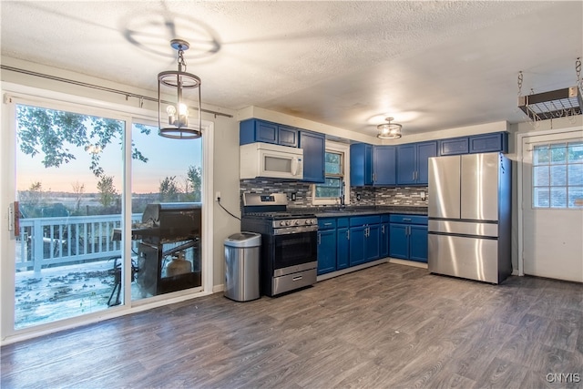 kitchen with dark wood-type flooring, appliances with stainless steel finishes, decorative light fixtures, and blue cabinets