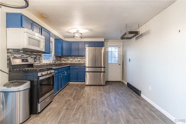 kitchen featuring backsplash, stainless steel appliances, dark wood-type flooring, sink, and blue cabinets