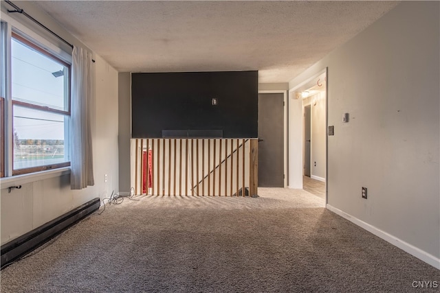 carpeted spare room with a baseboard heating unit and a textured ceiling