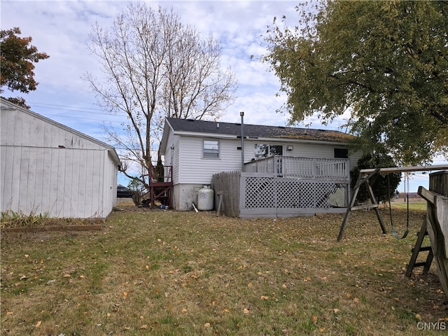 rear view of house featuring a wooden deck and a lawn