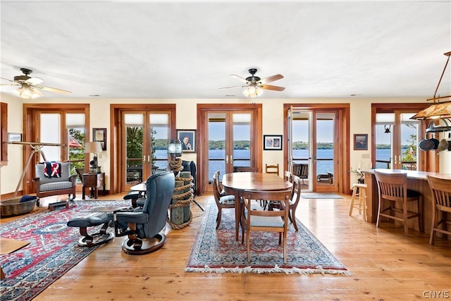 dining room featuring french doors, a water view, ceiling fan, and light hardwood / wood-style flooring