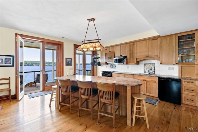 kitchen featuring pendant lighting, dishwasher, sink, a water view, and french doors