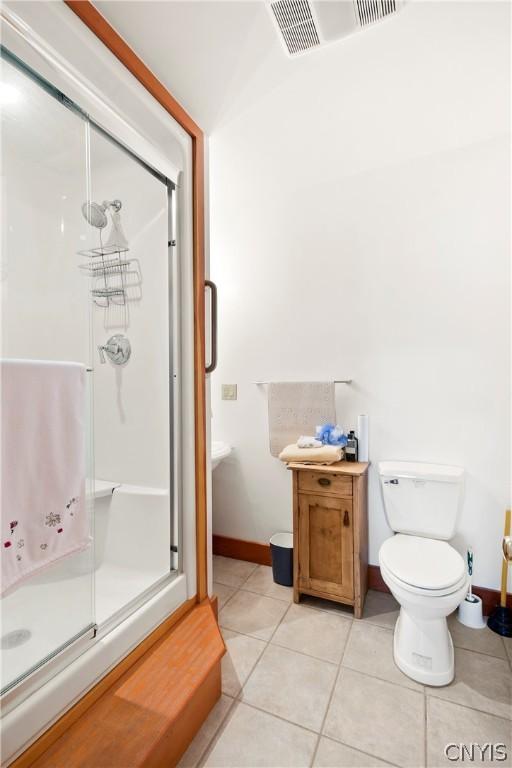 bathroom featuring an enclosed shower, tile patterned floors, and toilet