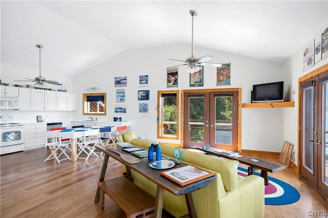 dining space with lofted ceiling, sink, light hardwood / wood-style floors, and french doors