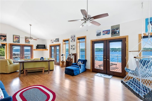 living room featuring lofted ceiling, hardwood / wood-style floors, a water view, a wealth of natural light, and french doors