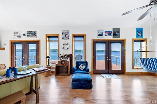 sitting room with french doors, a water view, and hardwood / wood-style flooring