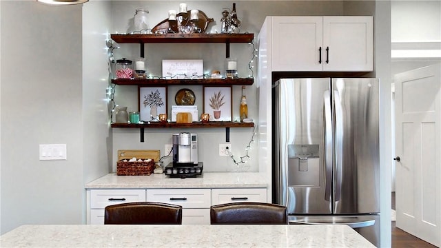 kitchen featuring white cabinets, stainless steel fridge with ice dispenser, and light stone counters